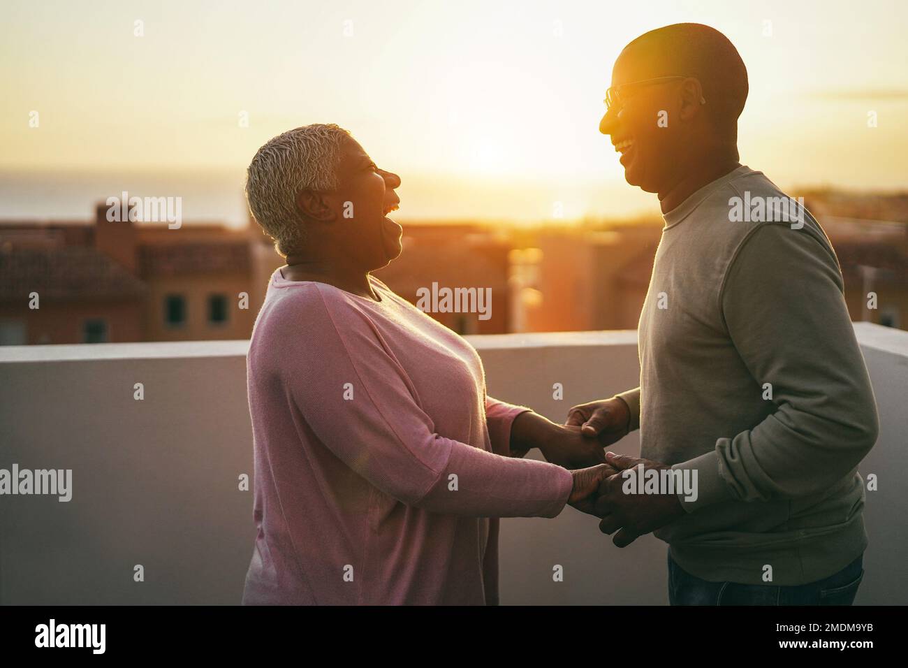 Senior african couple dancing outdoors with sunset on background - Focus on Stock Photo