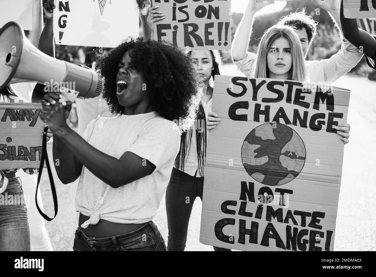 Young group of demonstrators on road from different culture and race protest for climate change - Focus on right sign - Black and white editing Stock Photo