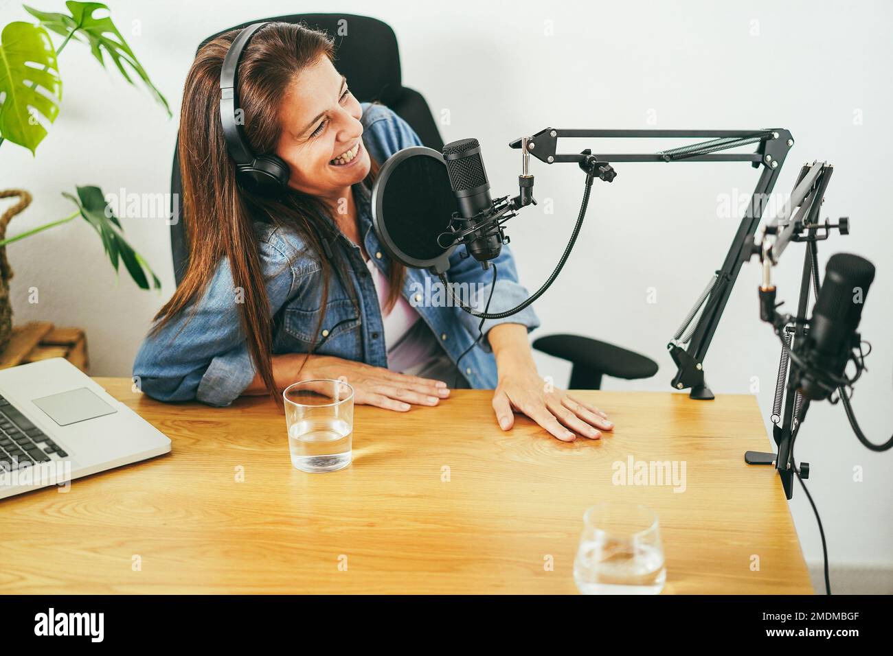 Hosts having podcast session together - Female speaker making an interview during live stream - Main focus on microphone Stock Photo