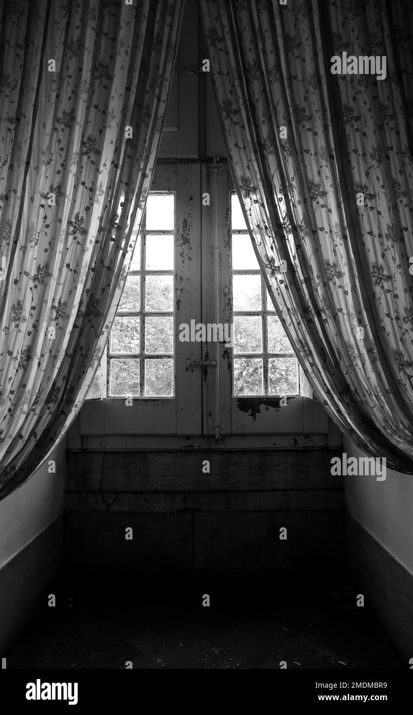 Window of old house with patterned curtain in Portugal. Monochrome