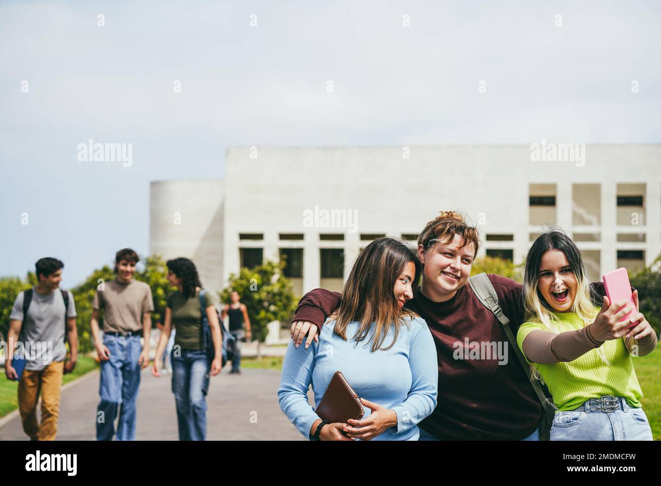 Young group of friends having fun doing selfie outside with school building on background - Focus on girls faces Stock Photo