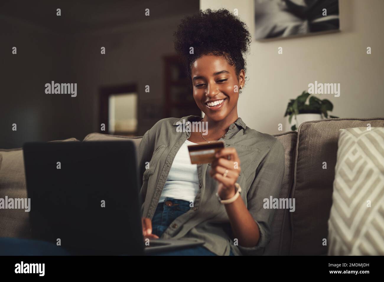 I always need more shoes. a beautiful young woman using her credit card and laptop while relaxing on a sofa at home. Stock Photo