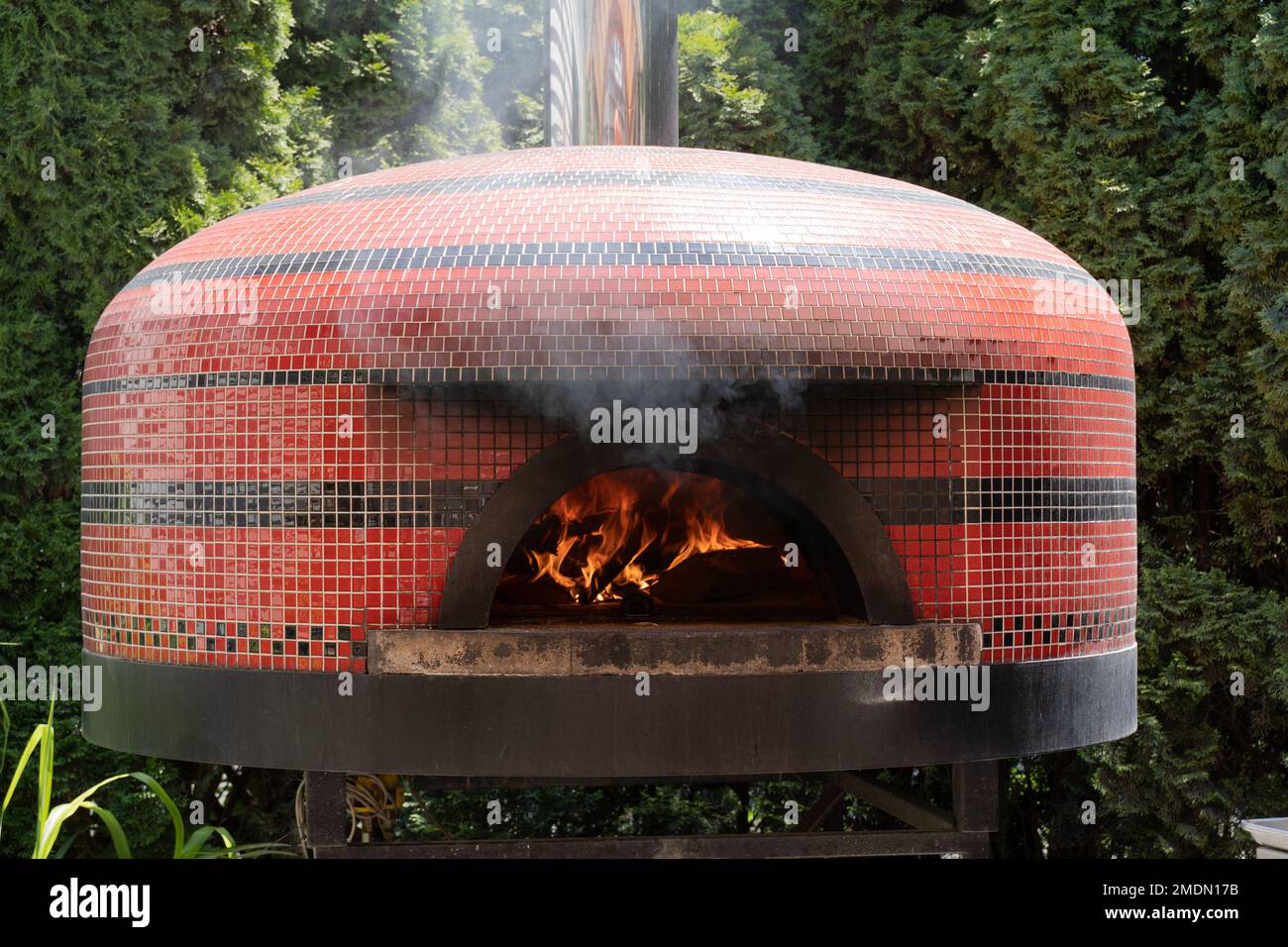 This outdoor pizza oven with wood fire warming the stove was in a small restaurant in the small Cape Cod town of Sandwich Stock Photo