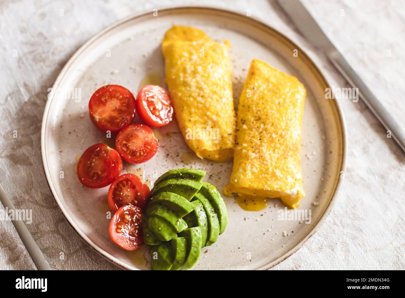 French omelette with tomatoes and avocado. Angle view on healthy breakfast. Stock Photo