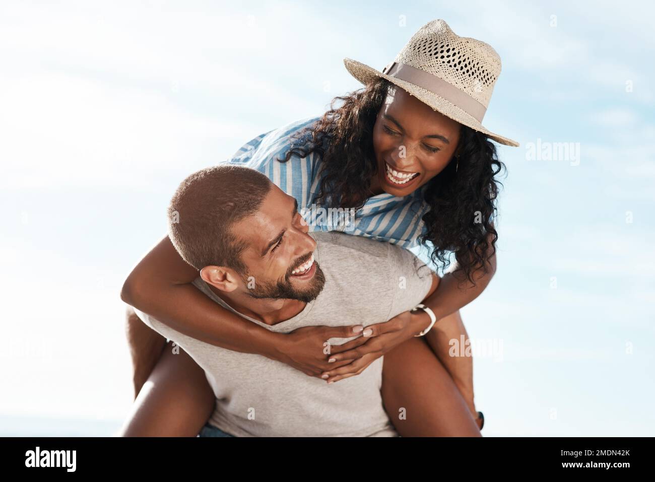 Your love lifts me higher. a young man piggybacking his girlfriend at the beach. Stock Photo