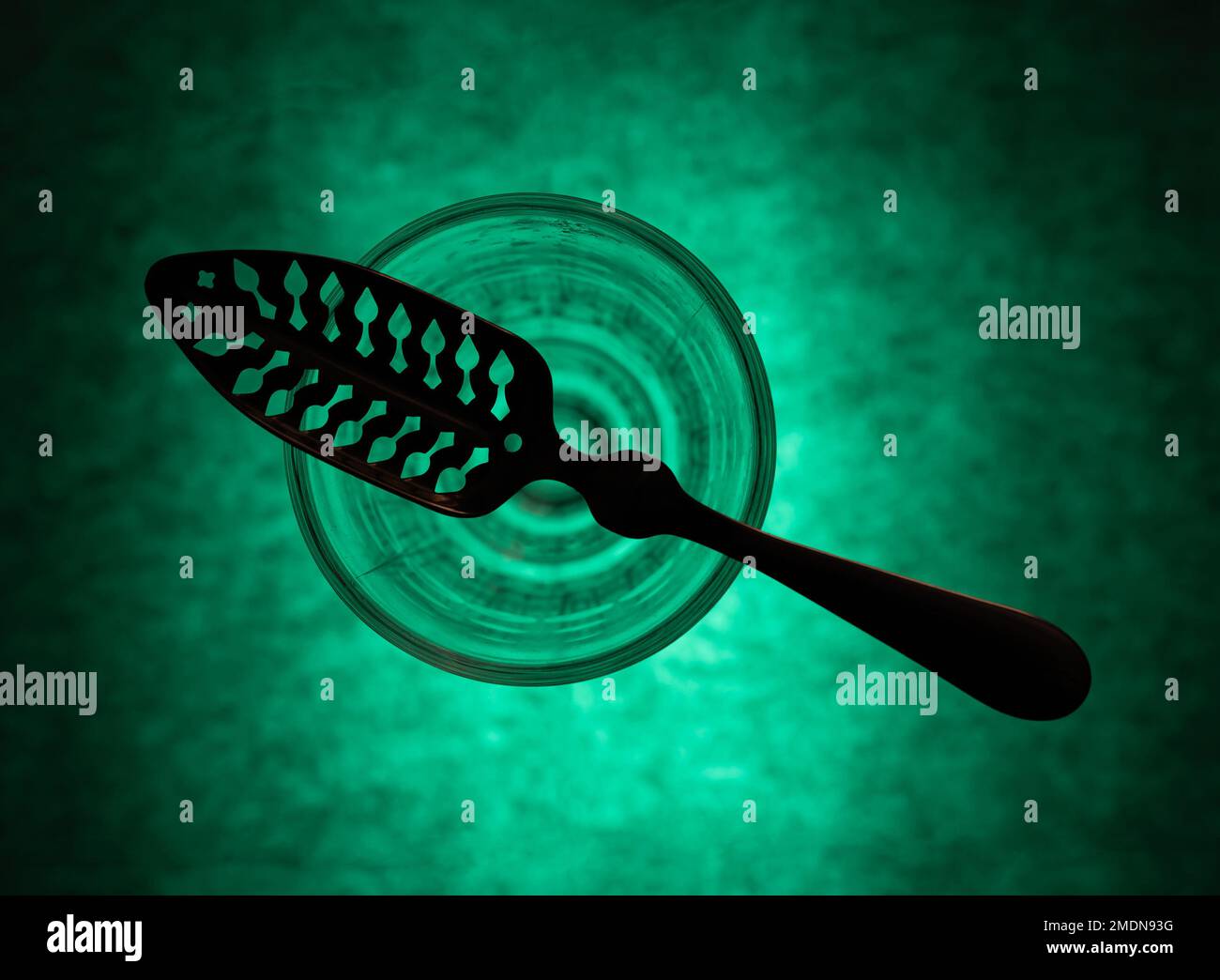 Traditional slotted absinthe spoon on the top of absinthe glass, flat lay, selective focus Stock Photo