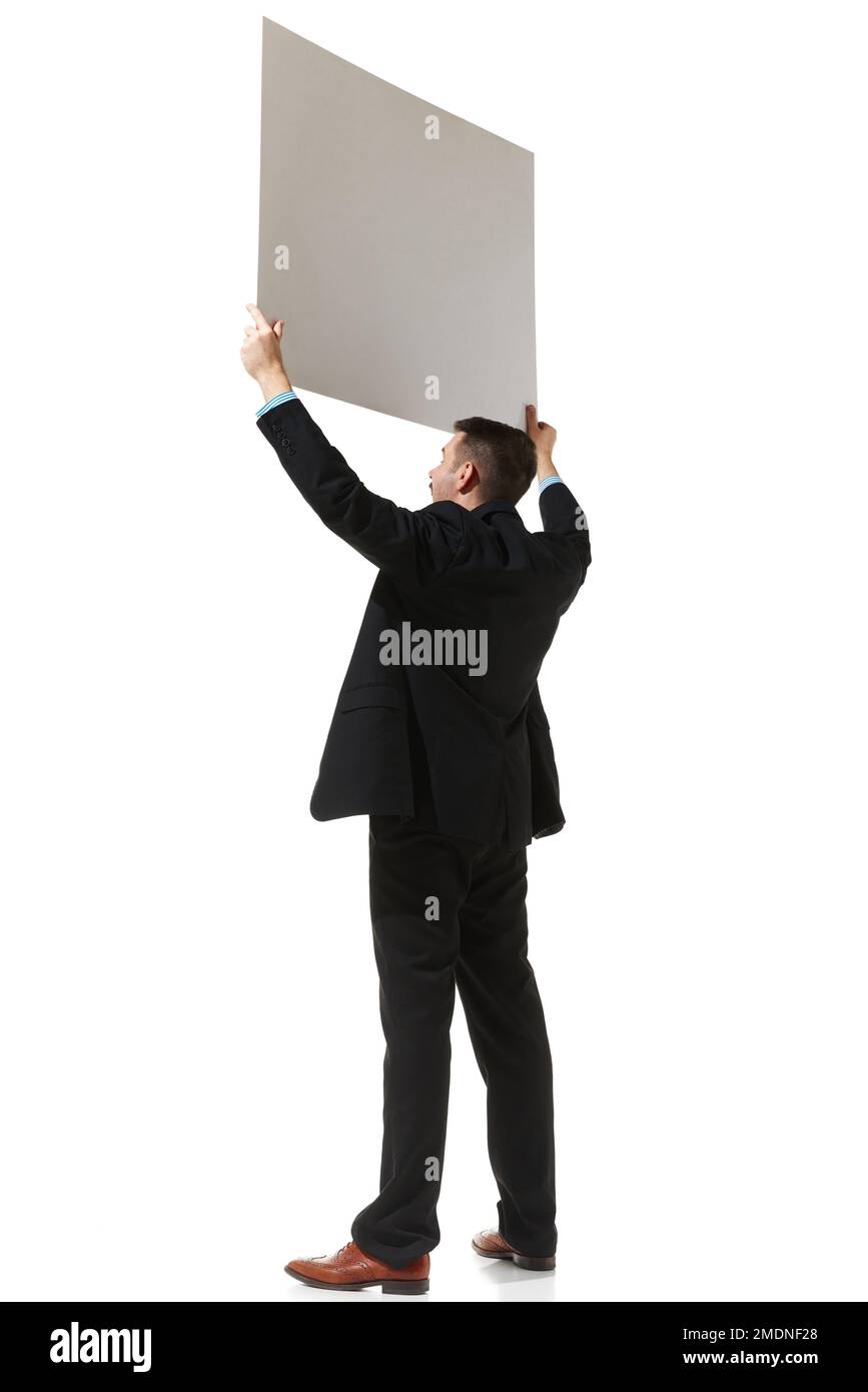 Side view. Businessman in a suit holding big empty paper for text over white studio background. Information. Concept of business, career, innovations Stock Photo