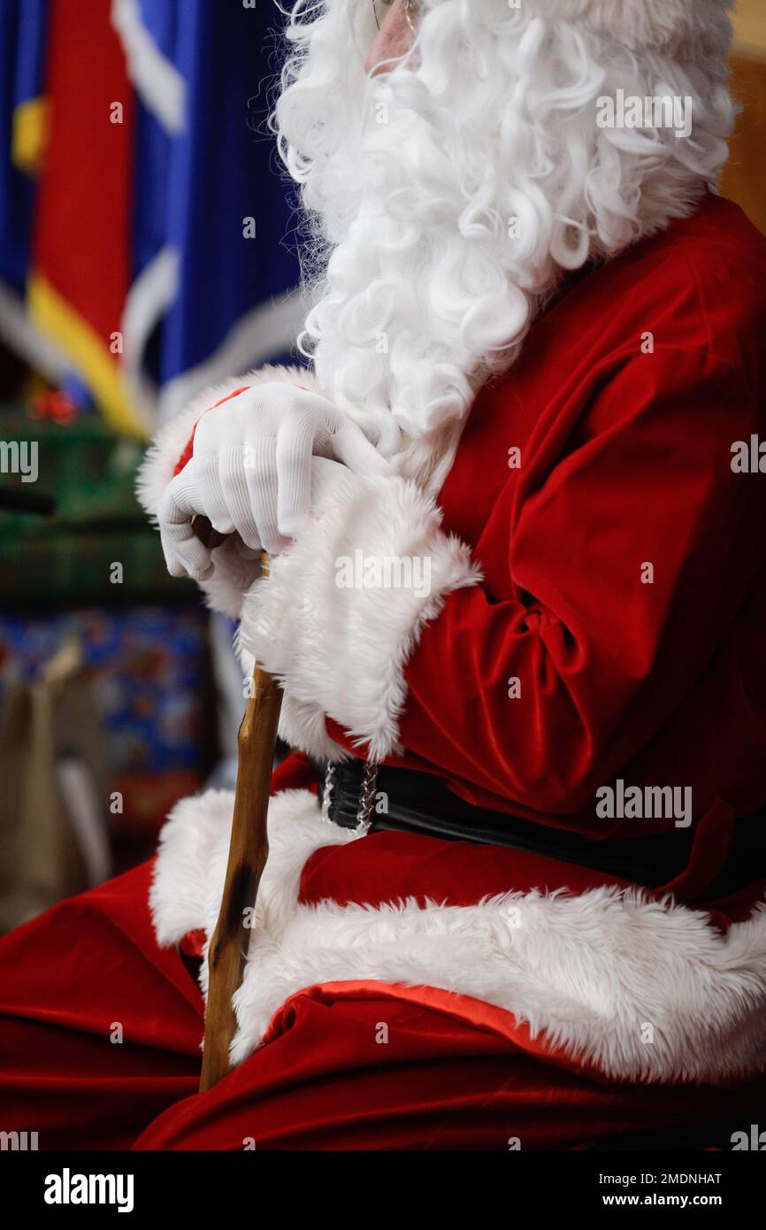 Shallow depth of field (selective focus) details with the Santa Claus costume of a man during a children's Christmas party. Stock Photo