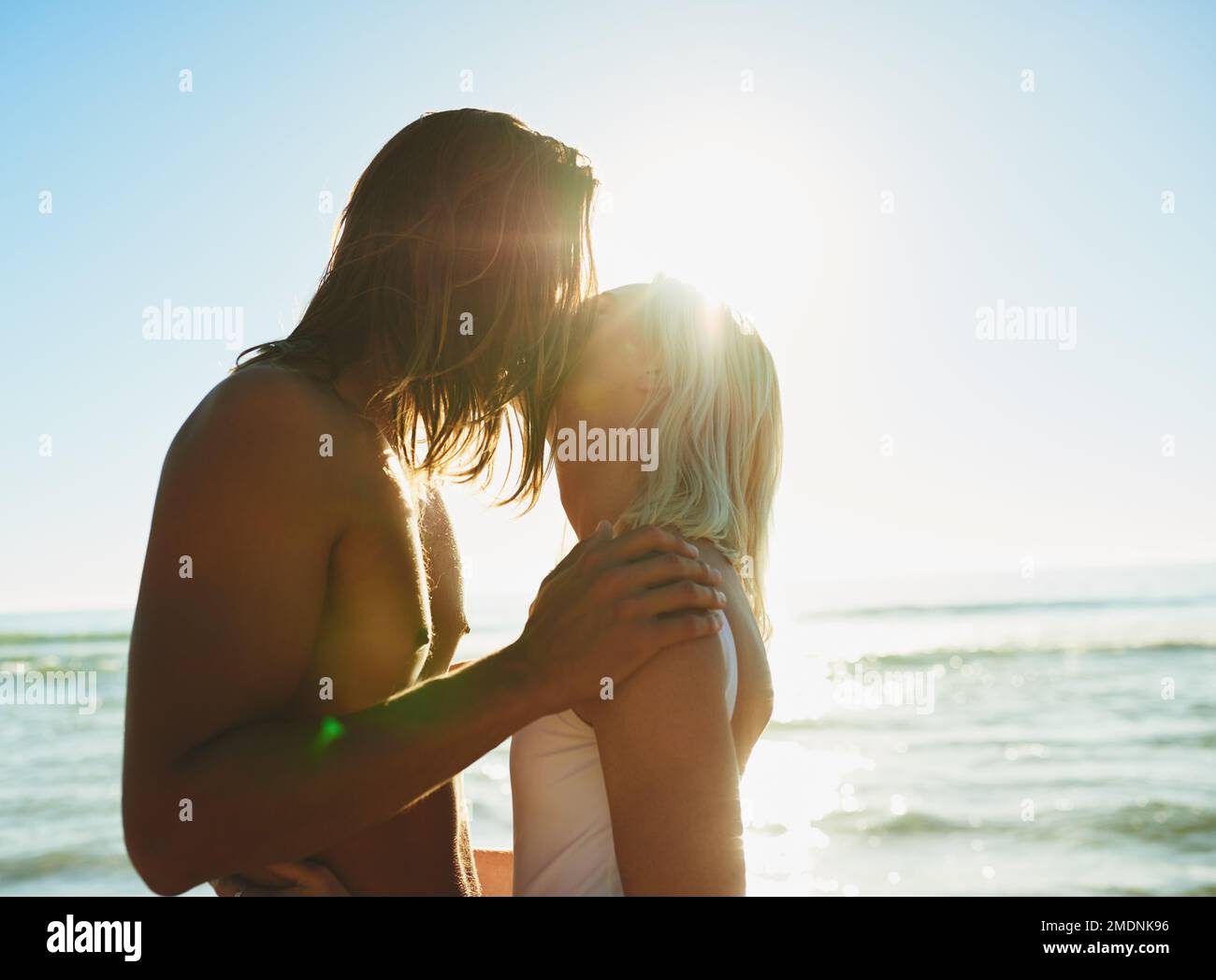 Youre the sunshine to all my days. an affectionate young couple kissing each other at the beach. Stock Photo