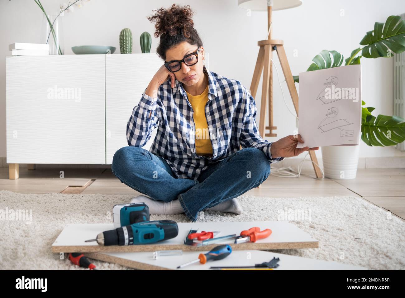 Black woman reading furniture assembly instruction manual in new home