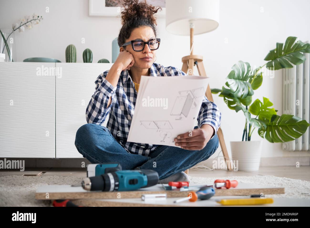 Black woman reading furniture assembly instruction manual in new home