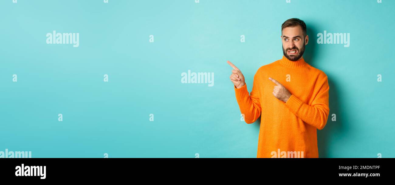 Displeased man cringe from something bad, pointing and looking at ...