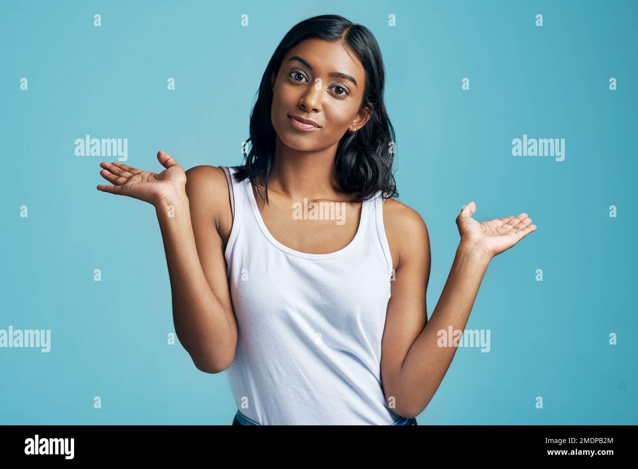 No worries. Studio portrait of a beautiful young woman shrugging her shoulders against a blue background. Stock Photo