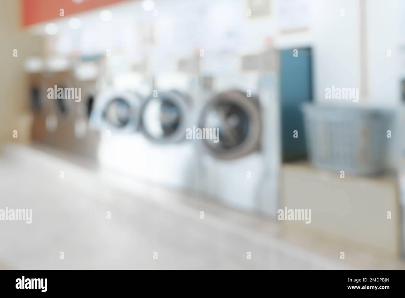 Blur background of of qualified coin-operated washing machines in a public store. Concept of a self service commercial laundry and drying machine in a Stock Photo