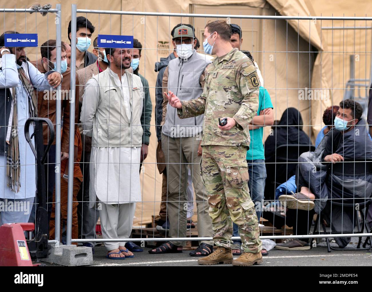 A soldier talks to people at the Ramstein U.S. Air Base in Ramstein, Germany,  Monday, Aug. 30, 2021. The largest American military community overseas houses  thousands Afghan evacuees in a tent city