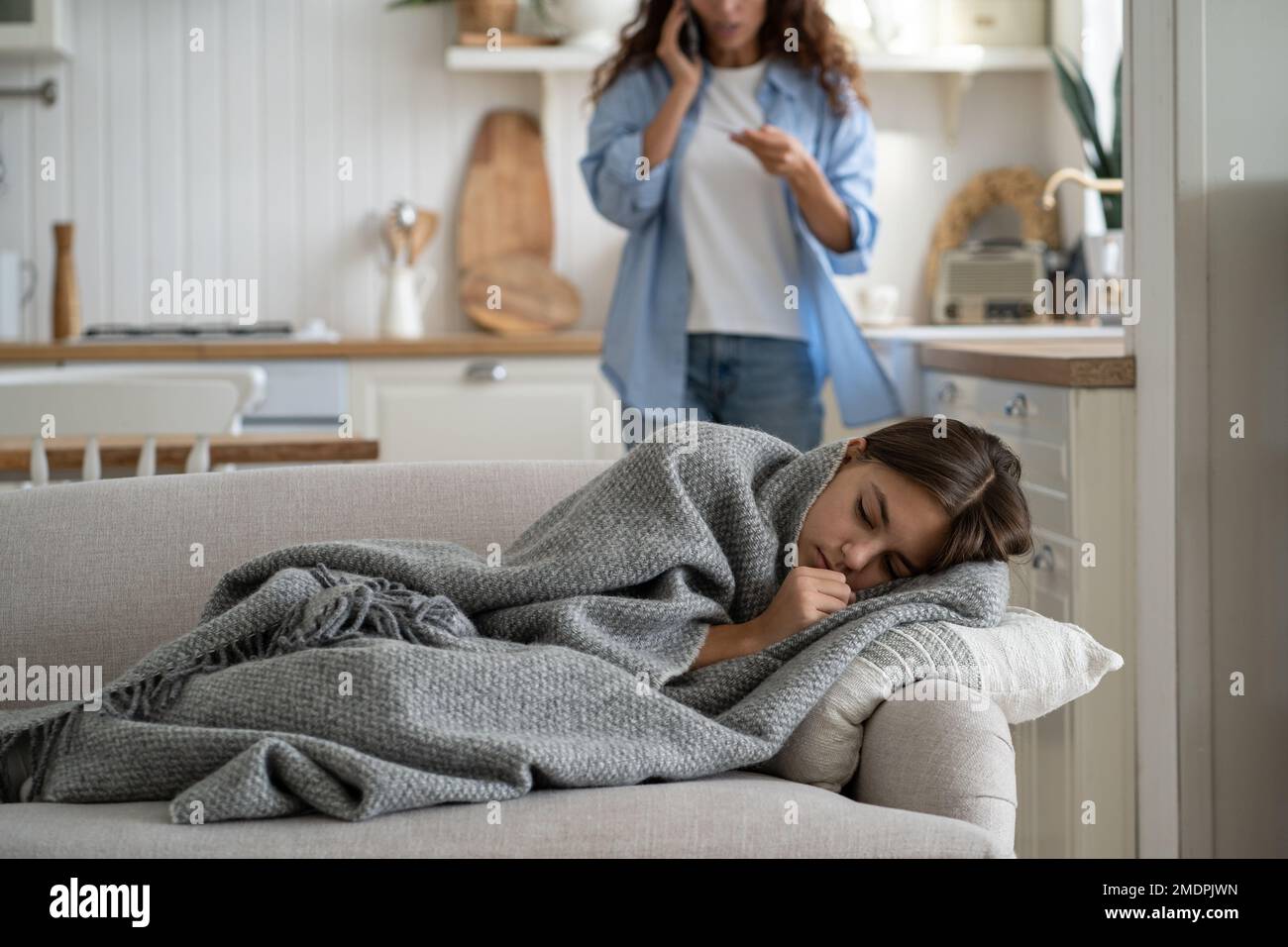 Sick child having fever and flu symptoms lying on sofa while her