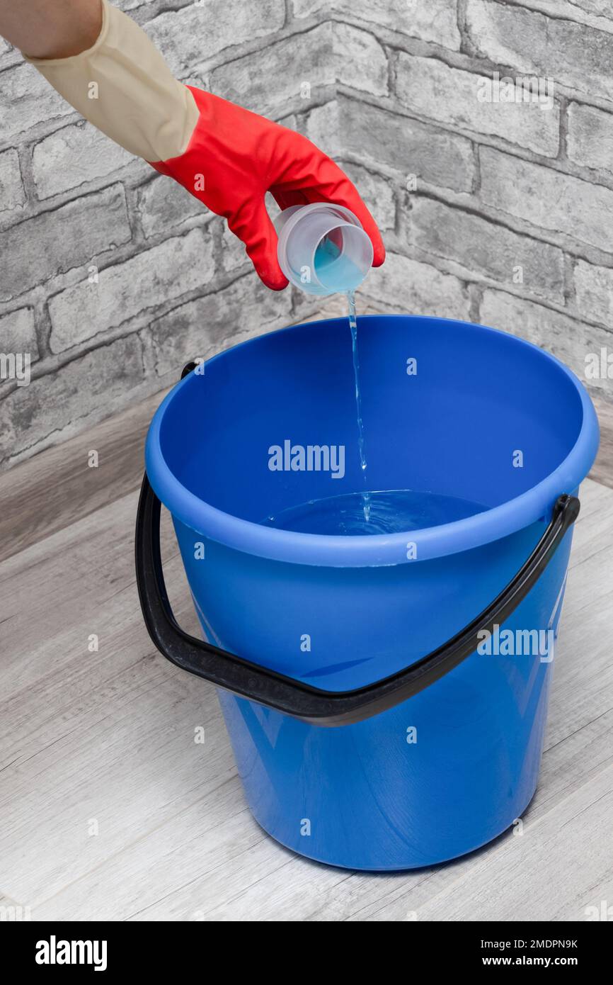 man adding detergent to a bucket of water. detergent for cleaning. wet