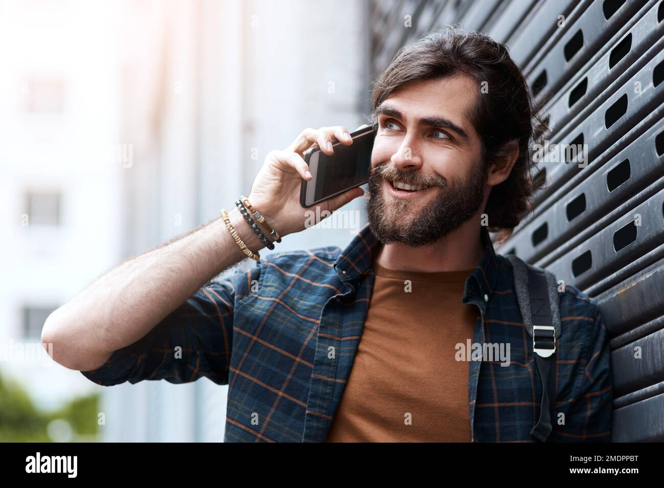 That sounds too good to be true. a handsome young man using his cellphone while walking in the city. Stock Photo