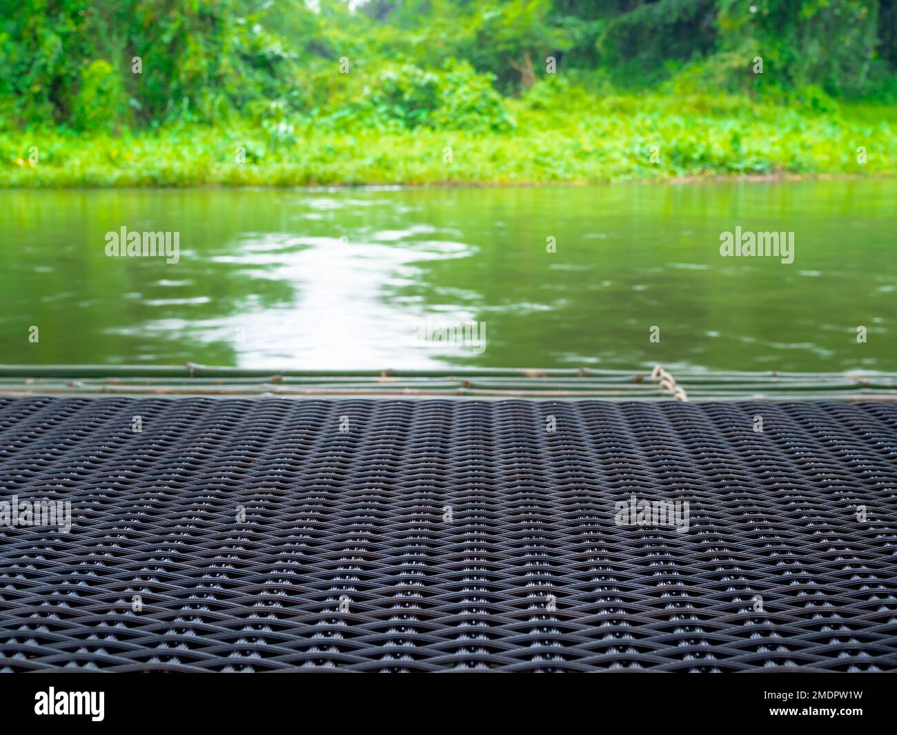 Close-up empty blank space on surface of rattan weave bed, furniture on stream river view with green forest background. Natural green background for s Stock Photo