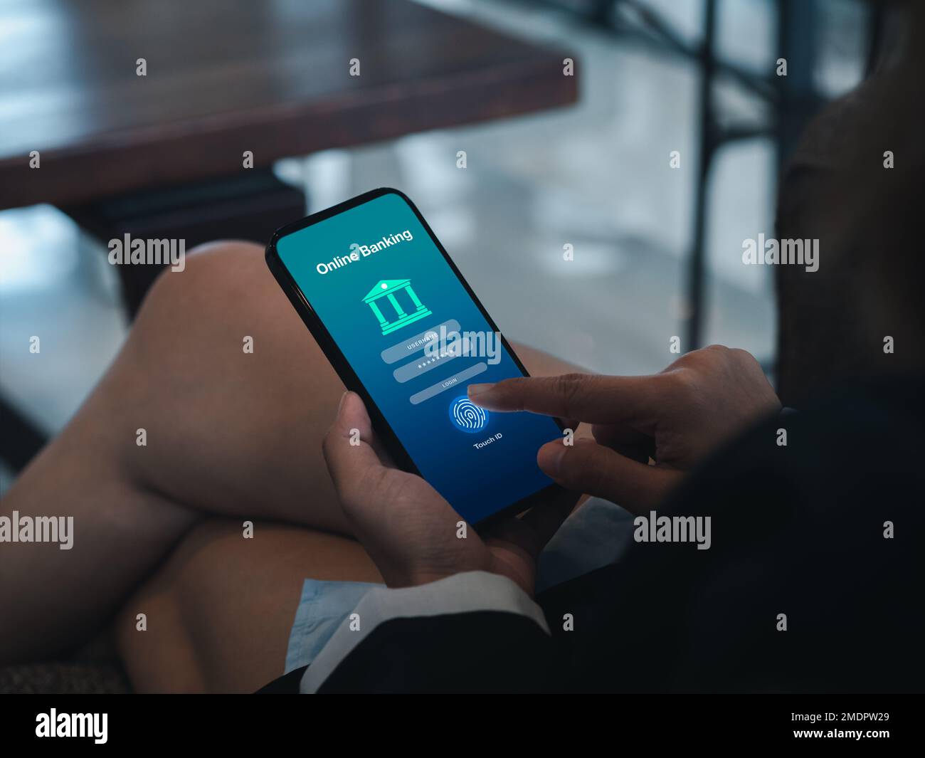 Mobile banking concept. Online banking application page on smart mobile phone screen holding by businessperson hand scanning with fingerprint for logi Stock Photo