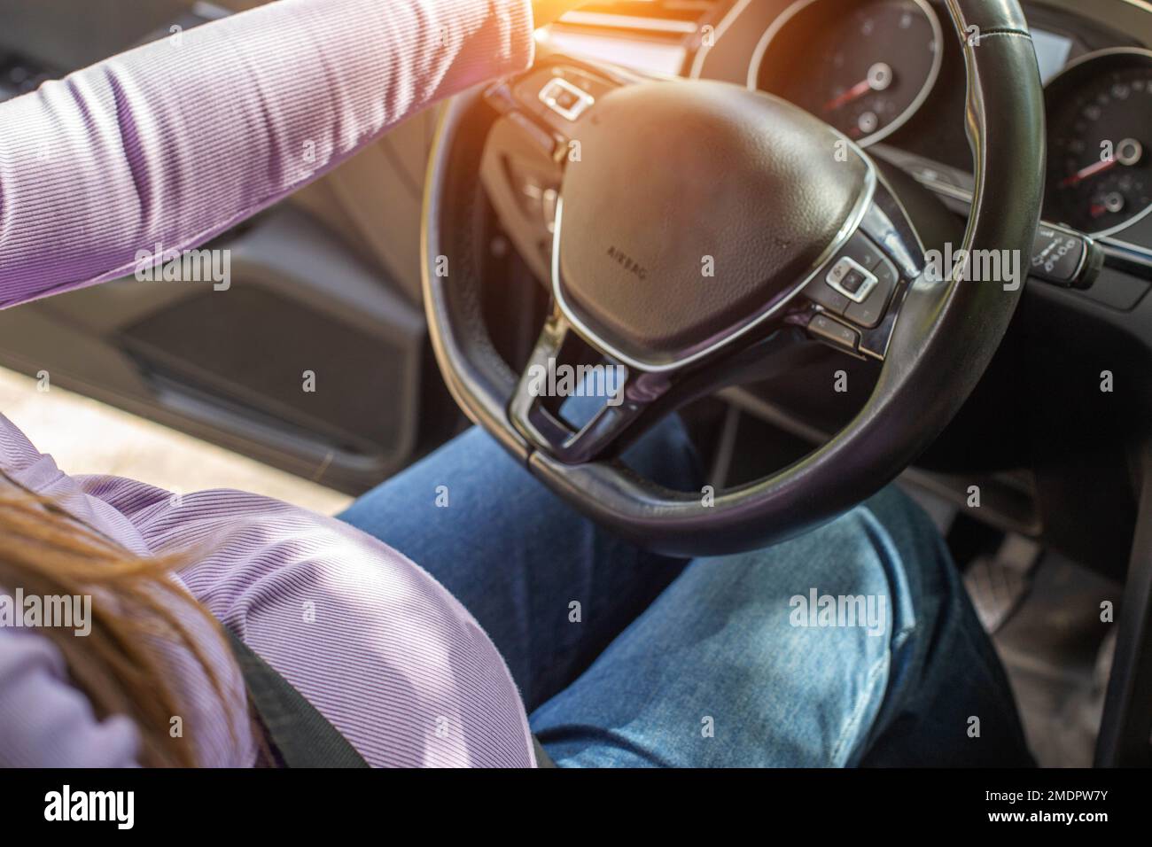 A pregnant woman wearing a seat belt drives a car. Safety and driving