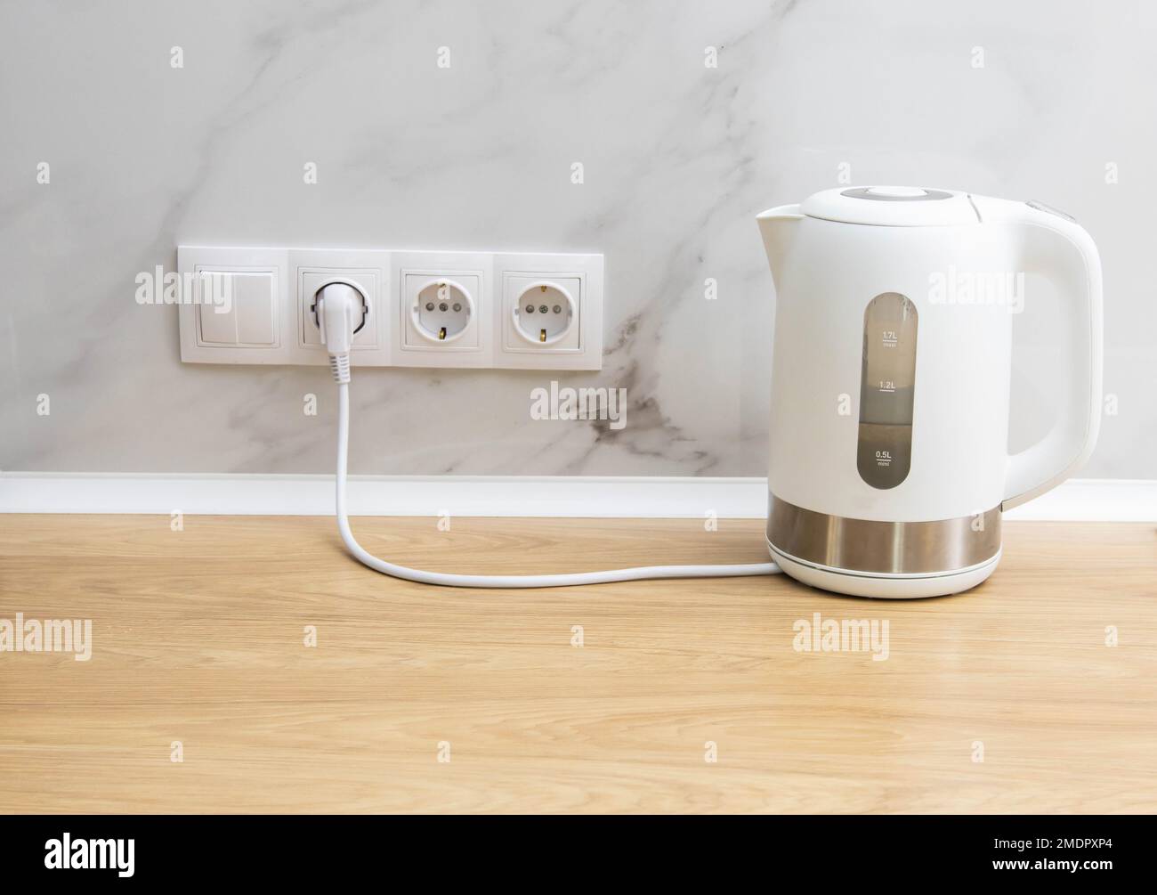 A white modern electric kettle stands on a table against the background of  sockets. Boiling water. Electricity consumption by household electrical app  Stock Photo - Alamy