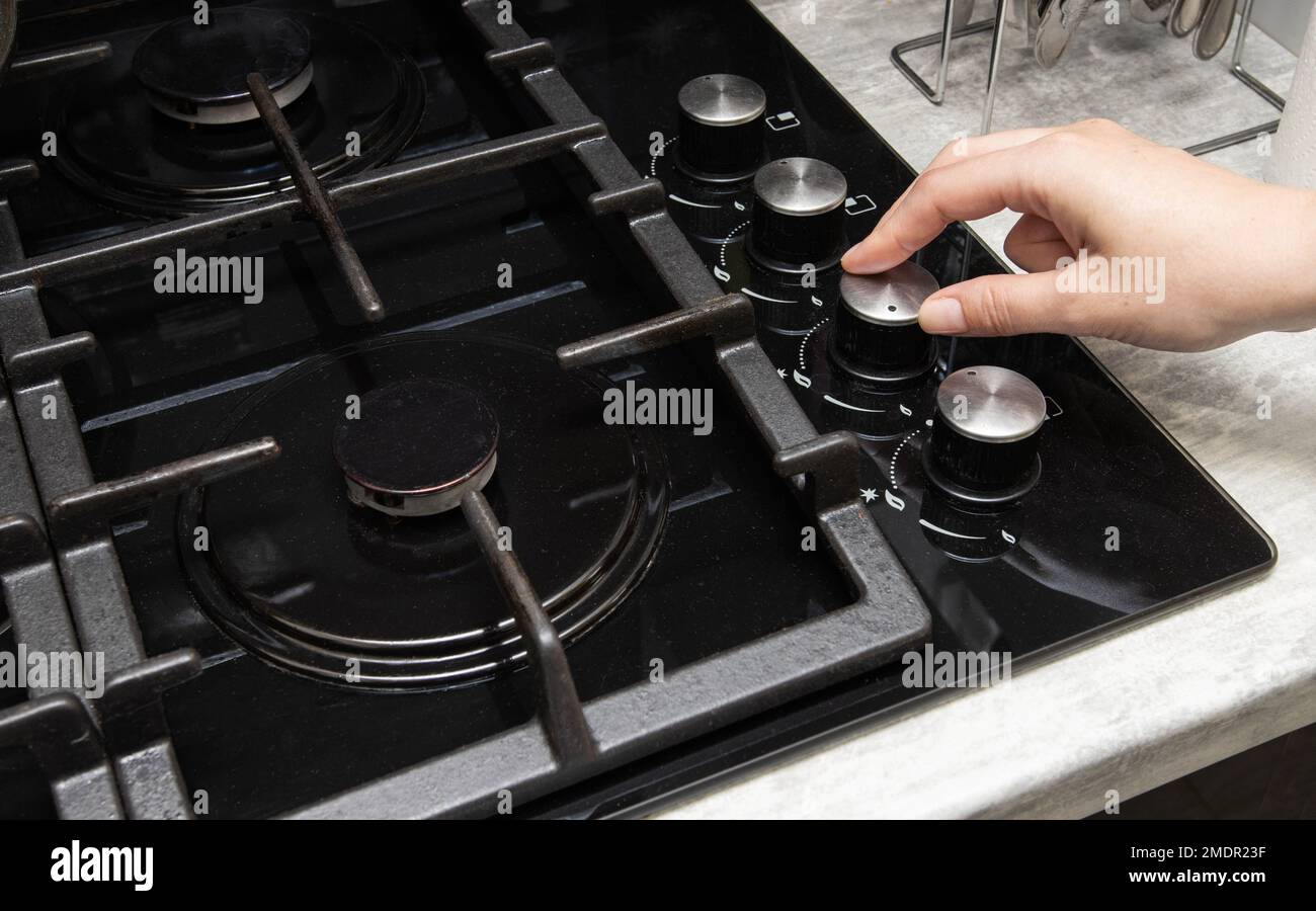 A woman turns on a gas stove with piezo ignition. Turns the gas