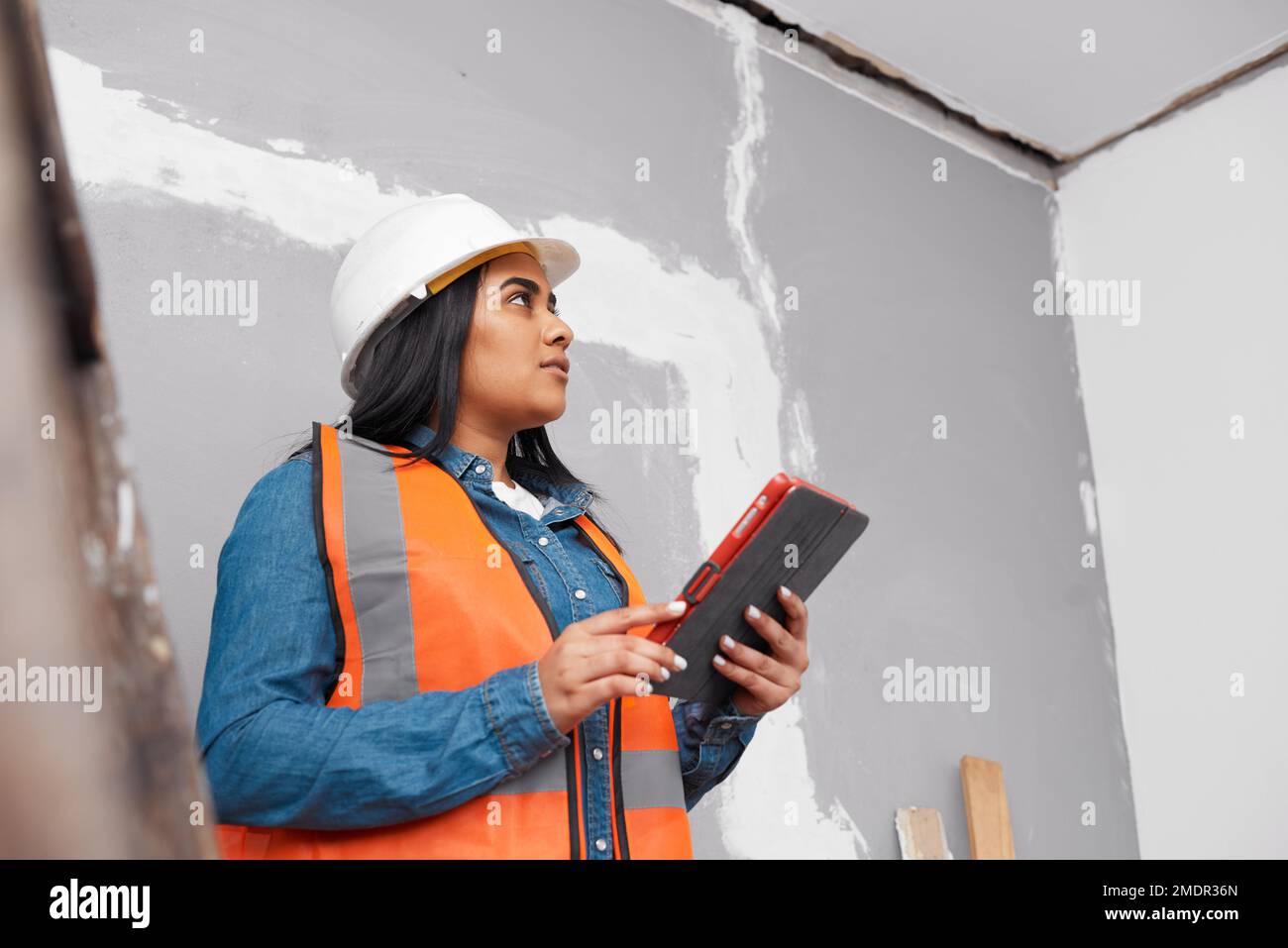 A young female South Asian construction worker uses tablet to log project Stock Photo