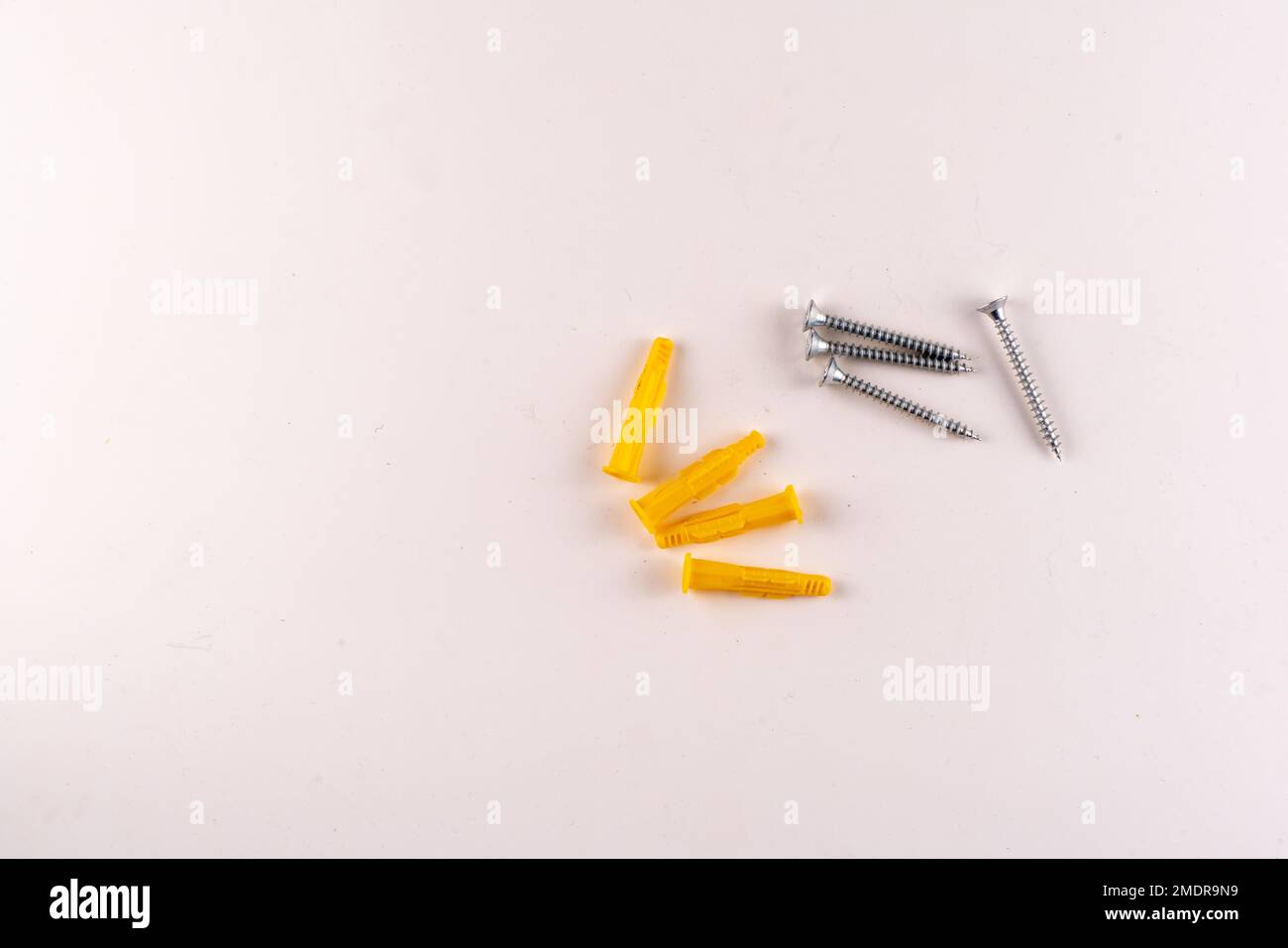 Set Of Screws And Yellow Plastic Screw Anchor Plugs With Text Area Isolated On White Background