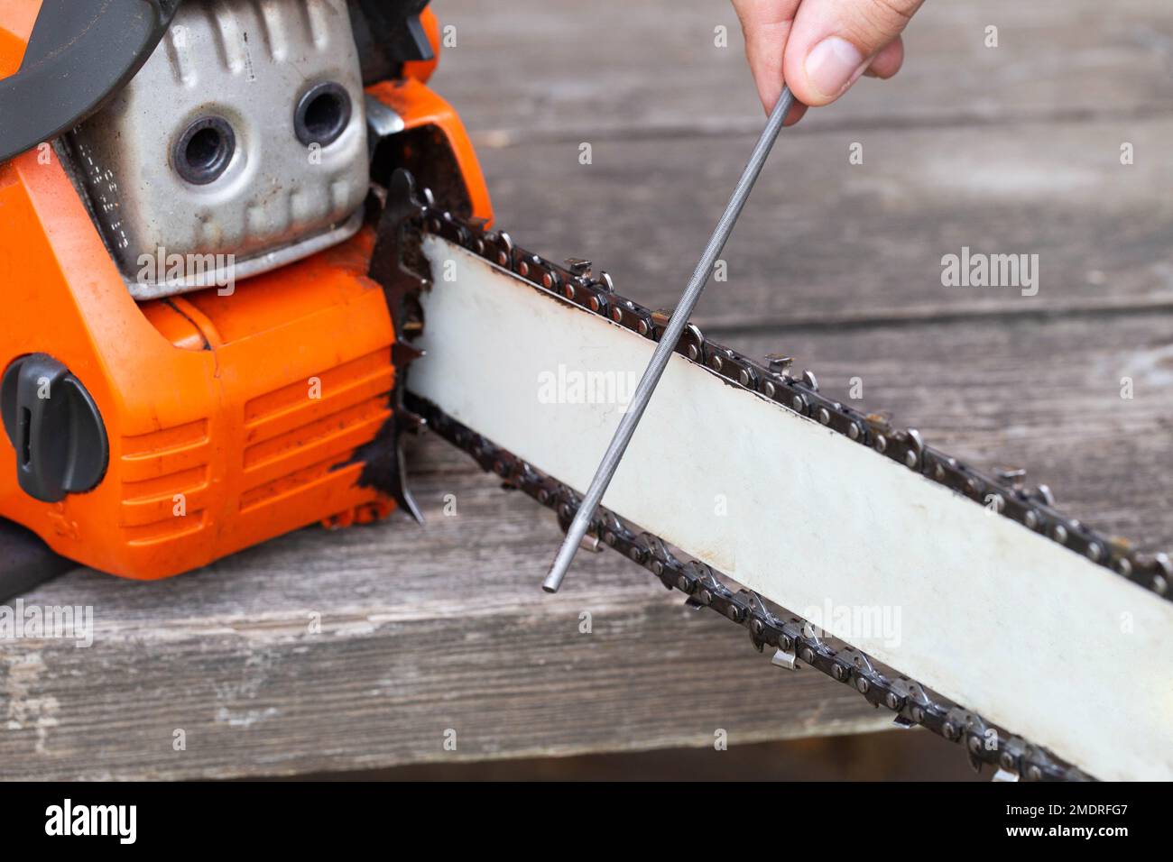 chainsaw chain sharpening with a special file. Dulling an old chain on a chainsaw bar Stock