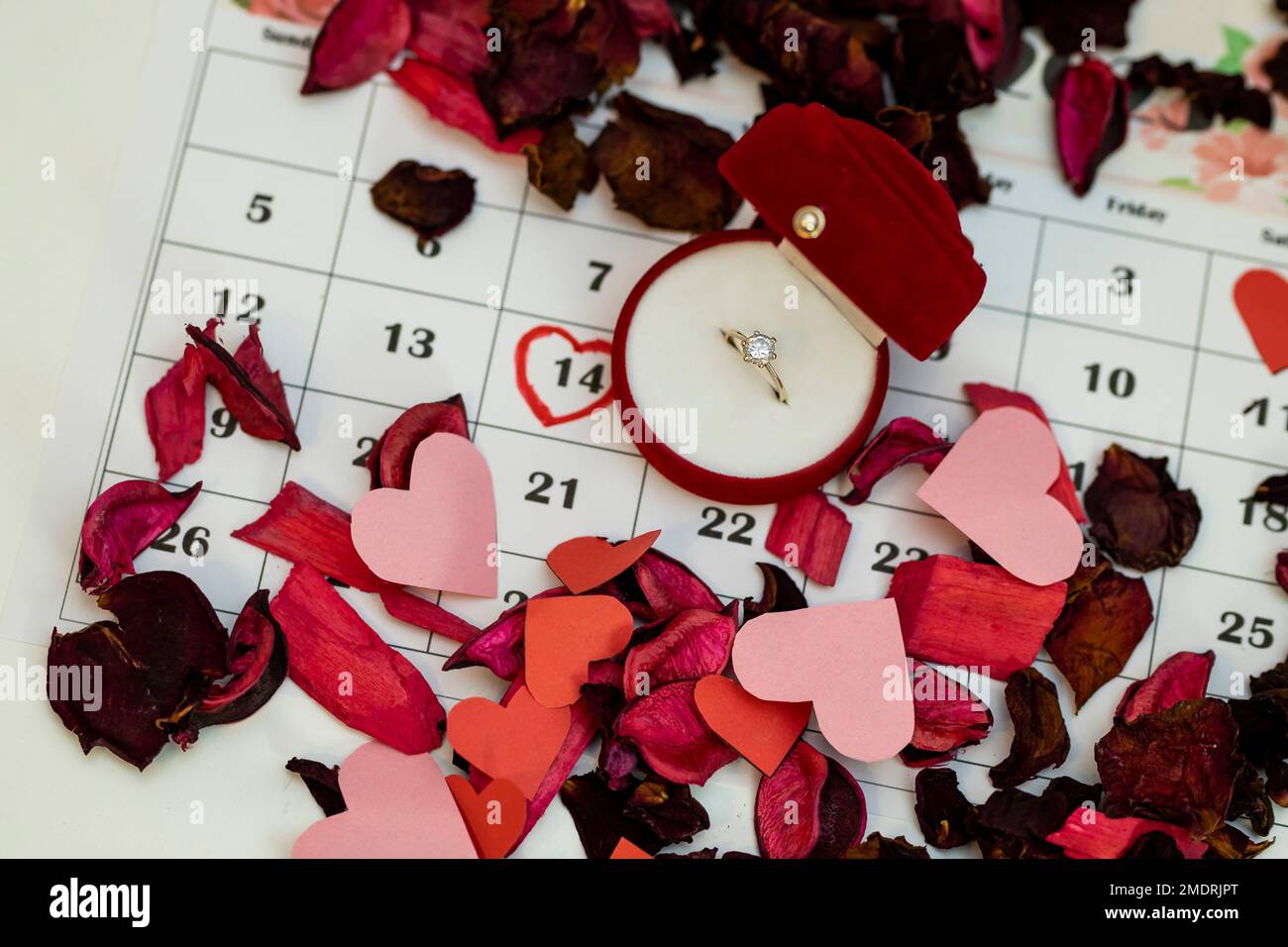 The ring box is placed on the calendar together with many flower petals