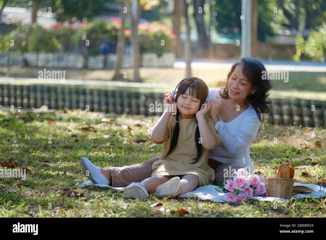 Asian Grandmother and Granddaughter hug together outdoor park. Hobbies and leisure, lifestyle, family life, happiness moment concept Stock Photo
