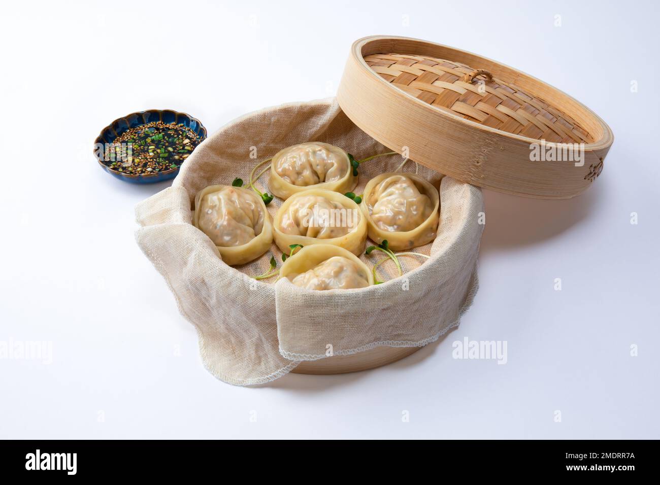 Delicious homemade Korean kimchi dumplings in a bamboo steamer over white background. Stock Photo