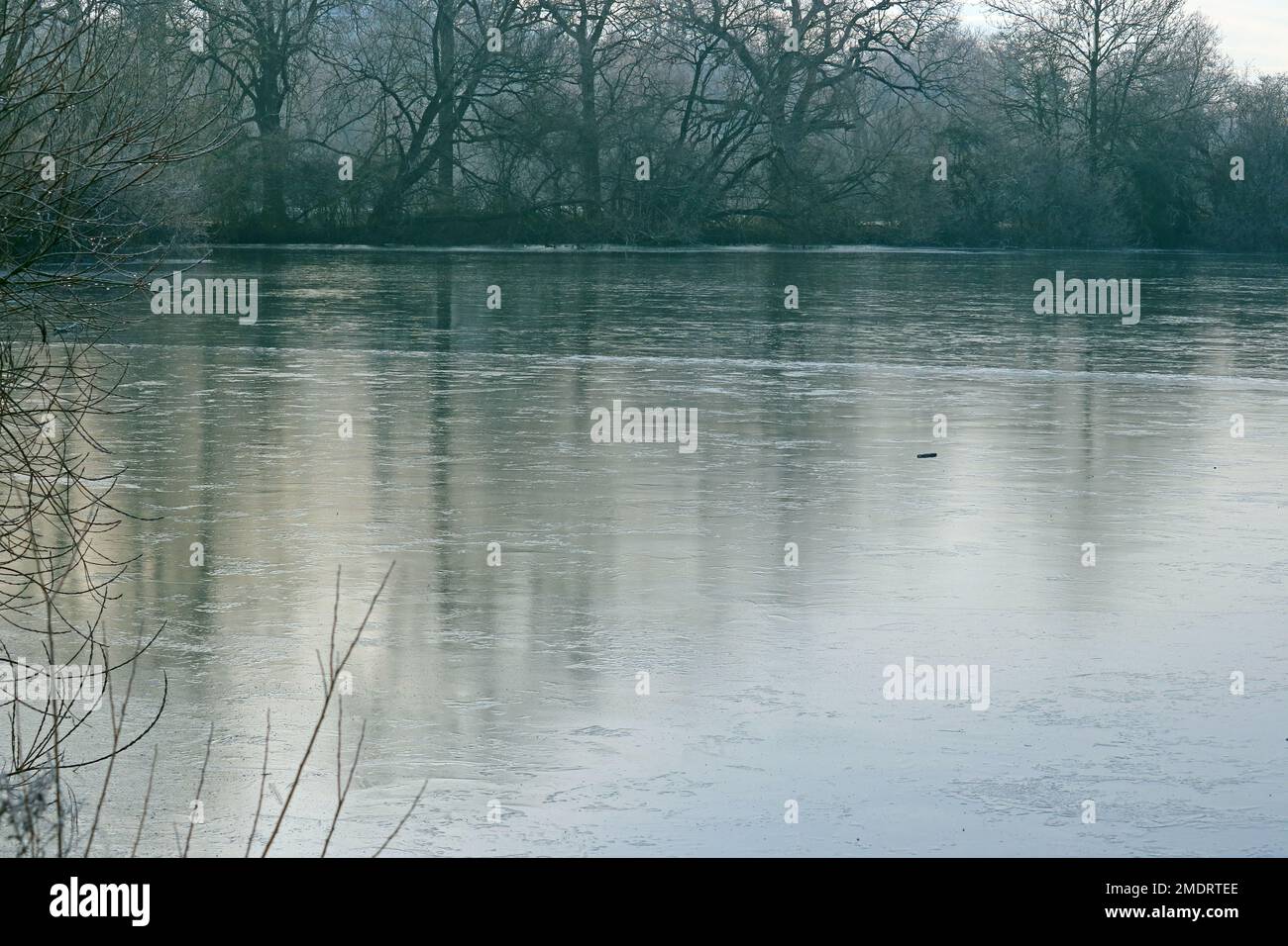 Frozen lake in the winter time. Ice across the water. Stock Photo