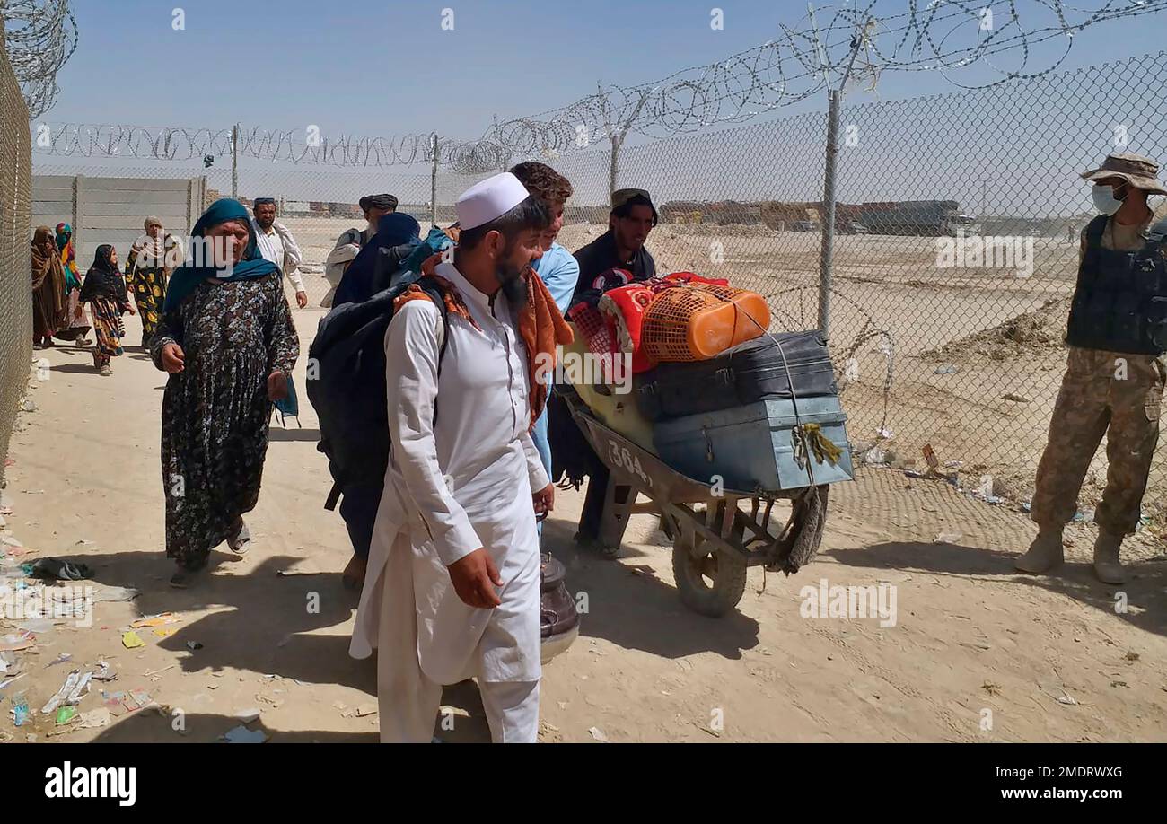 A Pakistani paramilitary soldier stands guard while Afghan families enter Pakistan through a border crossing point in Chaman, Pakistan, Tuesday, Aug. 24, 2021. (AP Photo/Jafar Khan) Stock Photo