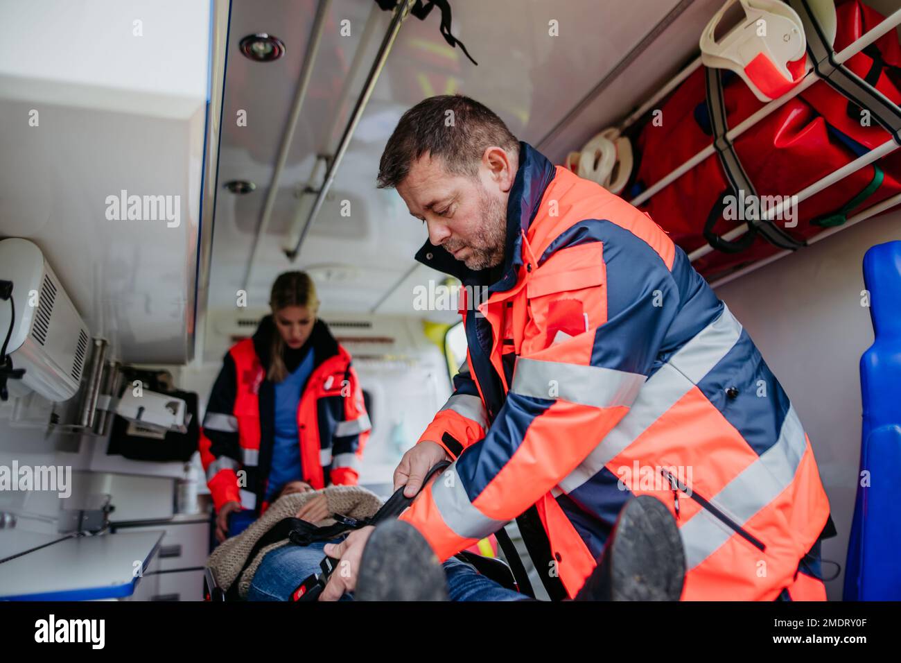 Rescuers taking care of patient, preparing her for transport. Stock Photo