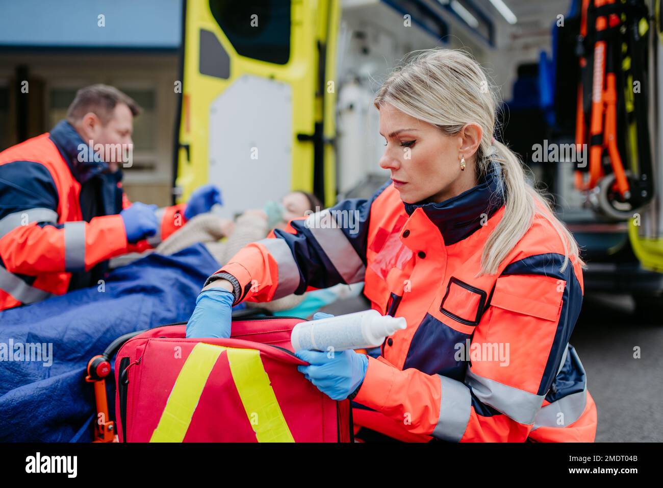 Rescuers taking care of patient, preparing her for transport. Stock Photo