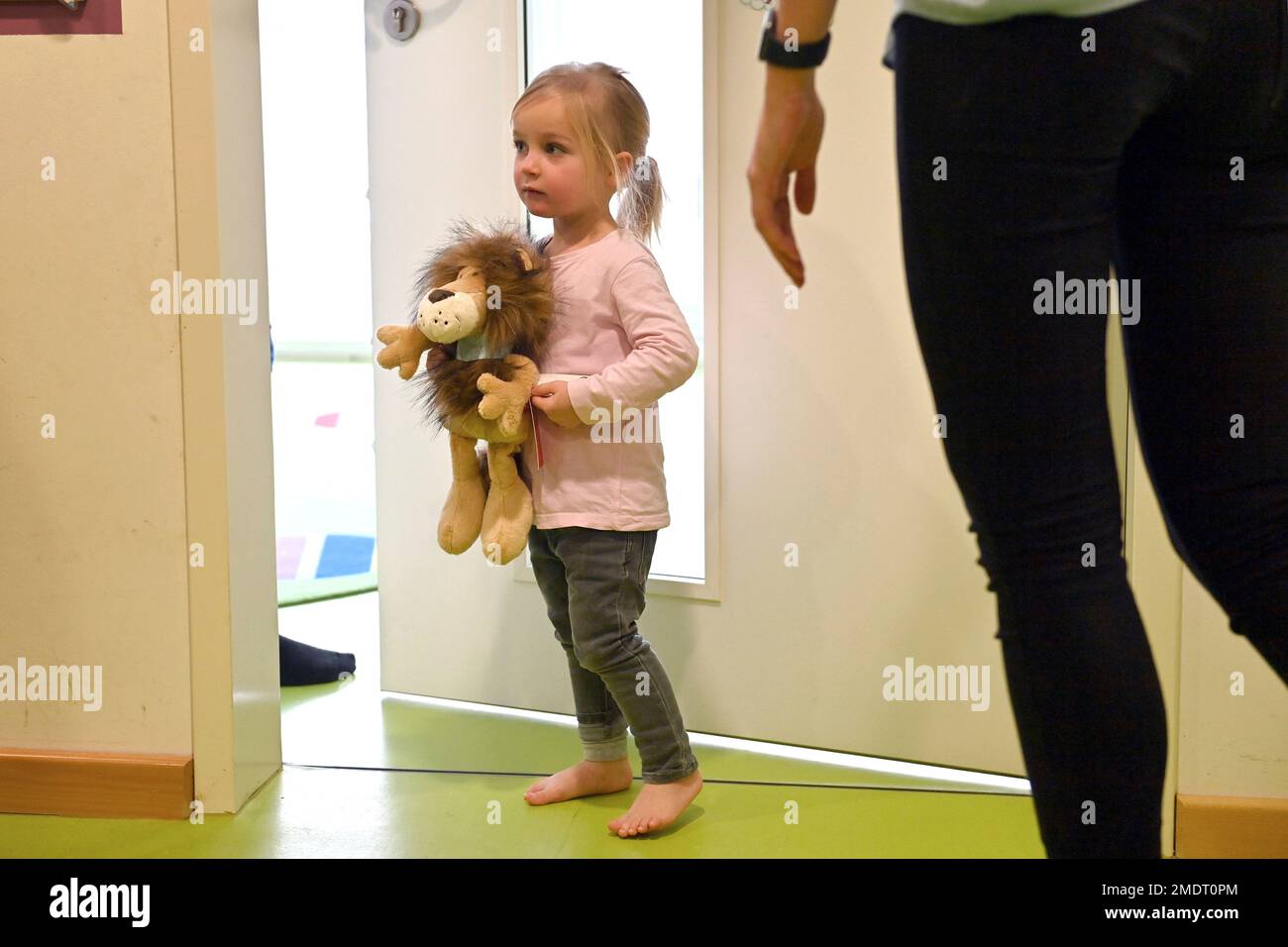Child, little girl without shoes, barefoot holding a plush toy in the