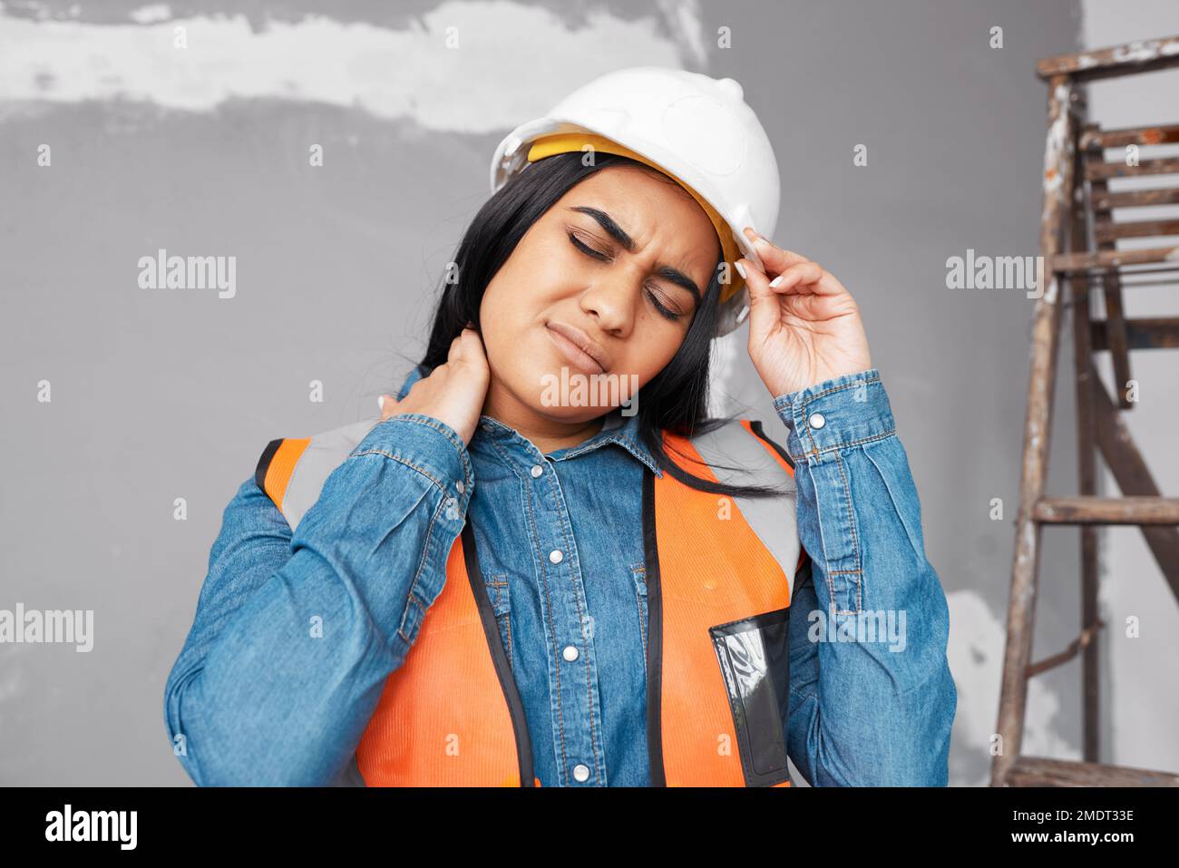 A young Indian construction worker holds her neck in pain from workplace injury Stock Photo