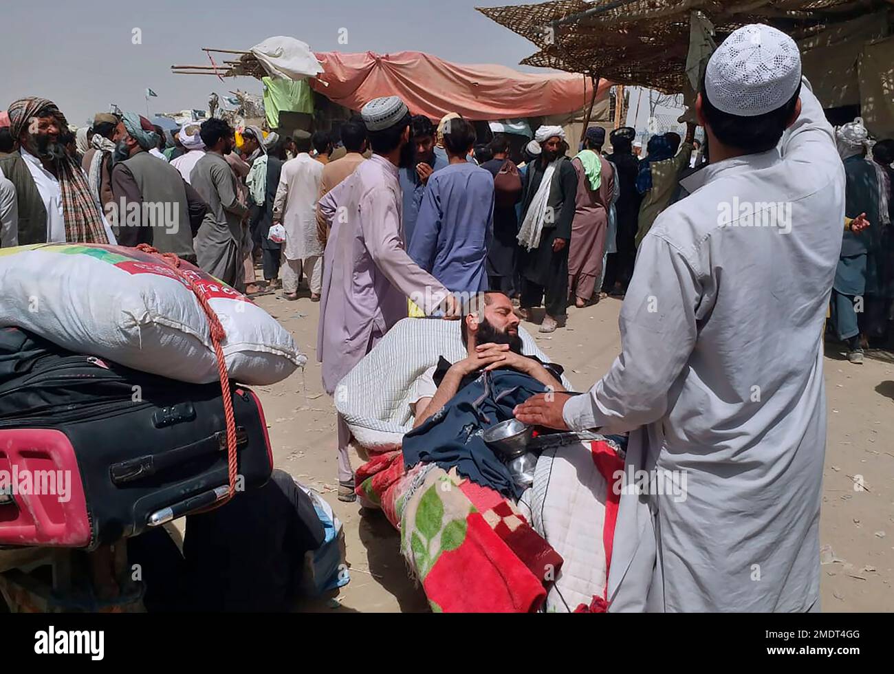 A porter pushes a wheelbarrow carrying a sick Afghan national as he and his relatives enter Pakistan through a border crossing point in Chaman, Pakistan, Monday, Aug. 23, 2021. Chaman is a key border crossing between Pakistan and Afghanistan that normally thousands cross daily along with a steady stream of trucks transporting goods to Afghanistan. (AP Photo/Jafar Khan) Stock Photo