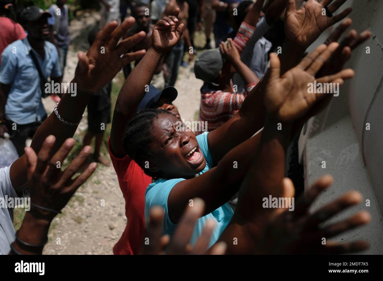 Earthquake victims reach for water being handed out during a food ...
