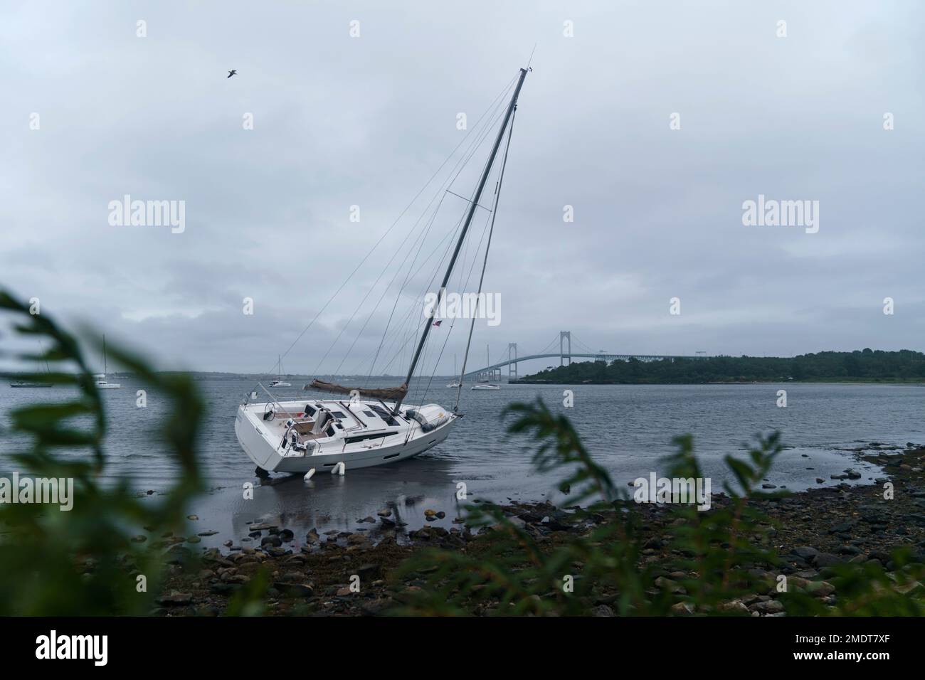 A sailboat sits washed up on shore after loose from its