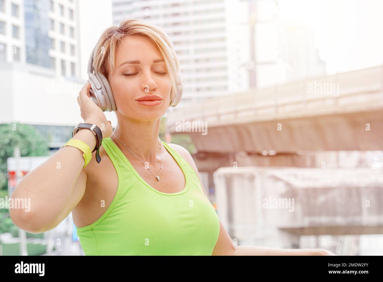 caucasian woman enjoy music with wireless headphone technology lifestyle in city background Stock Photo