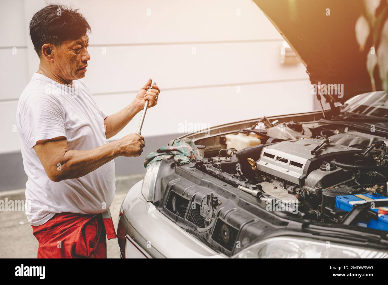 Asian male garage mechanic worker fix replace oil engine service repair broken car Stock Photo