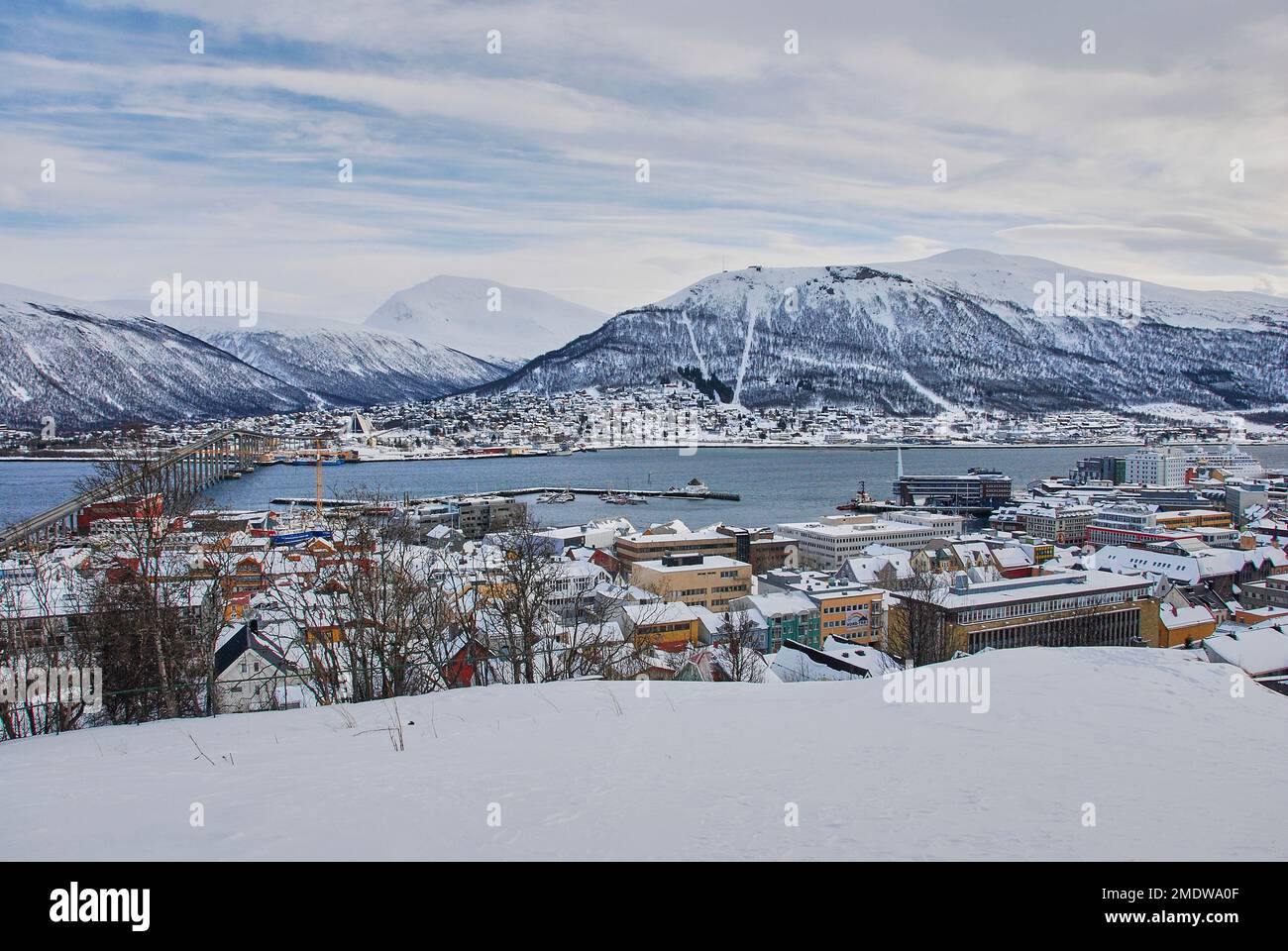 winter landscape of the port of Tromso in a fjord at the coastline of northern Norway with snow covered mountains in the background Stock Photo