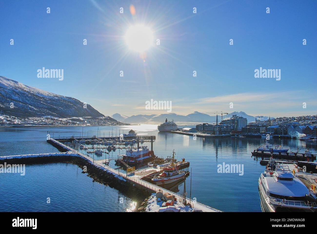Cruise ship in the winter landscape of the port of Tromso in a fjord at the coastline of northern Norway with snow covered mountains in the background Stock Photo