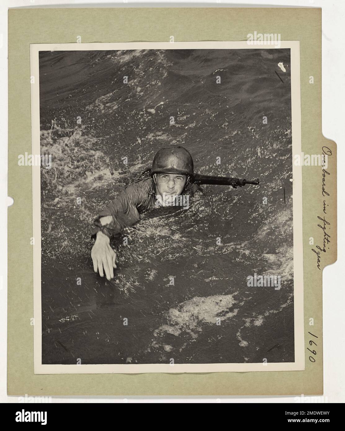 Overboard in Full Fighting Gear. A fighting Coast Guardsman is give rigorous training under battle conditions. Plunging into the sea, rifle, helmet and all, he swims for shore, preparing himself for such an emergency in the far-flung sea fronts of the war. Stock Photo