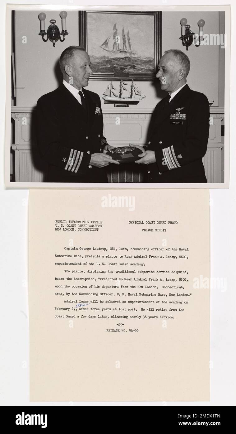 Captain George Lautrup, commanding officer of the Naval Submarine Base, presents a plaque to Rear Admiral Frank A. Leamy. Captain George Lautrup, USN, left, commanding officer of the Naval Submarine Base, presents a plaque to Rear Admiral Frank A. Leamy, USCG, superintendent of the U.S. Coast Guard Academy. The plaque, displaying the traditional submarine service dolphins, bears the inscription, 'Presented to Rear Admiral Frank A. Leamy, USCG, upon the occasion of his departure from the New London, Connecticut, area, by the Commanding Officer, U.S. Naval Submarine Base, New London.' Admiral Le Stock Photo