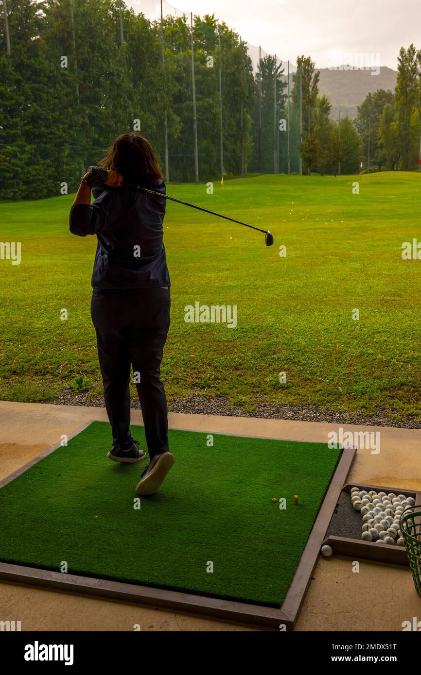 Golfer Training Her Golf Club Driver on Driving Range in a Rainy Day in