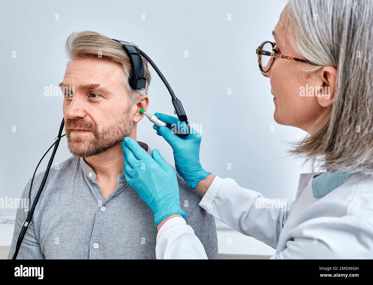 Experienced audiologist with tympanometer probe doing tympanometry